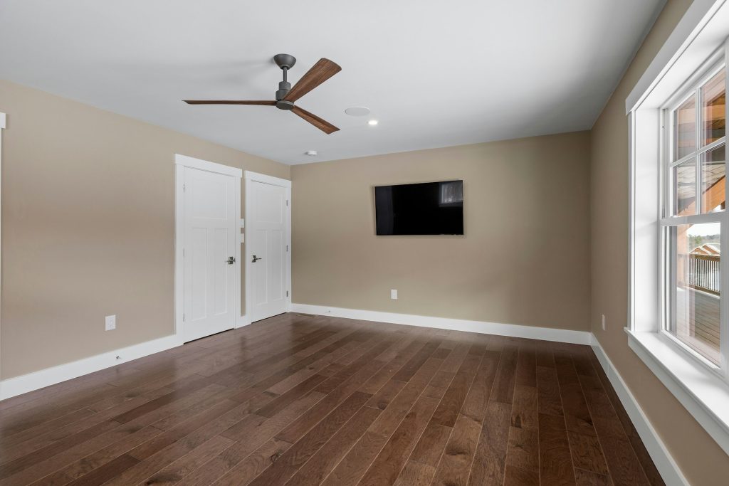 Empty room with a ceiling fan, hardwood floor and large windows