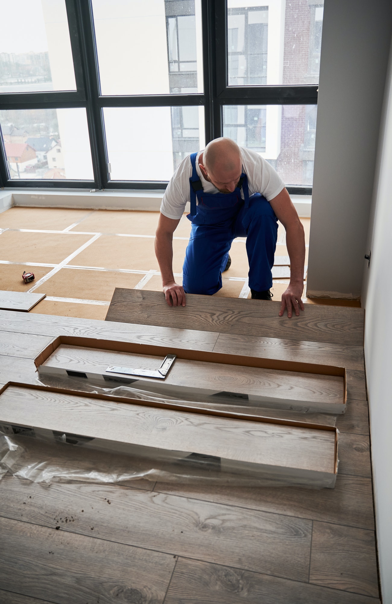 Man installing laminate flooring in apartment under renovation.